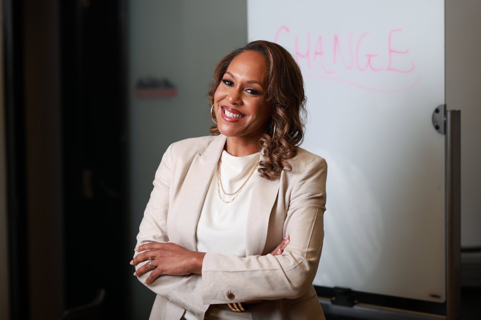 Janine Lequay with arms crossed in front of a whiteboard with the word change written on it